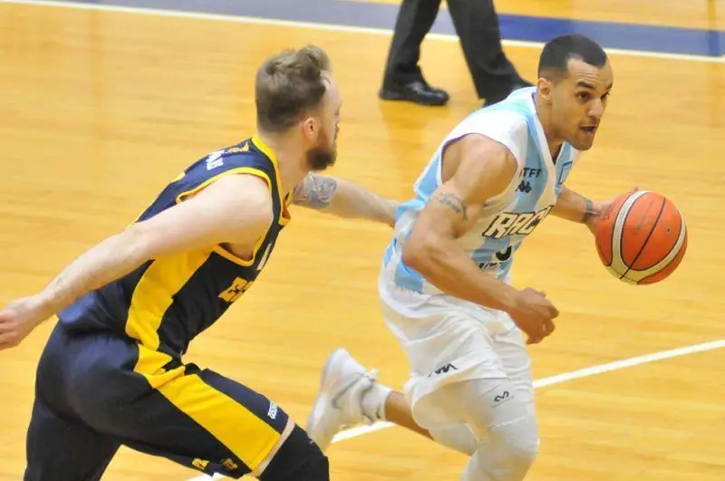 Jugador de básquet de Racing corre con la pelota.