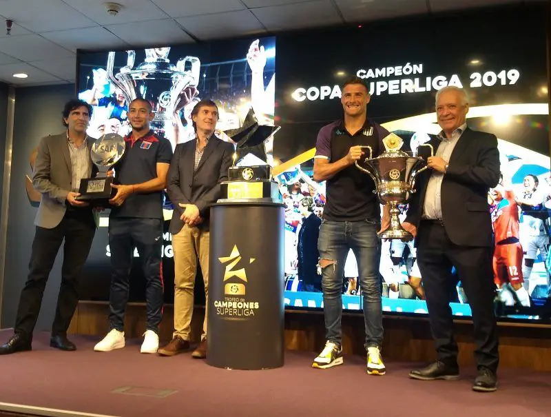 Pillud y Blanco, con el trofeo que disputarán Racing y Tigre